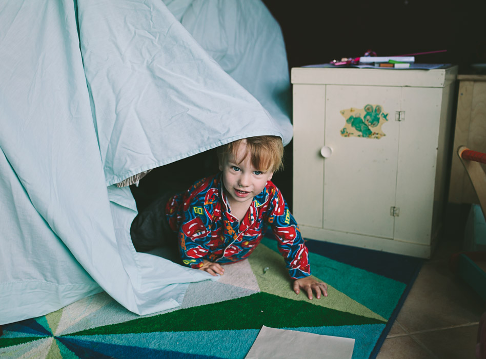 boy looking out of blanket and pillow forte