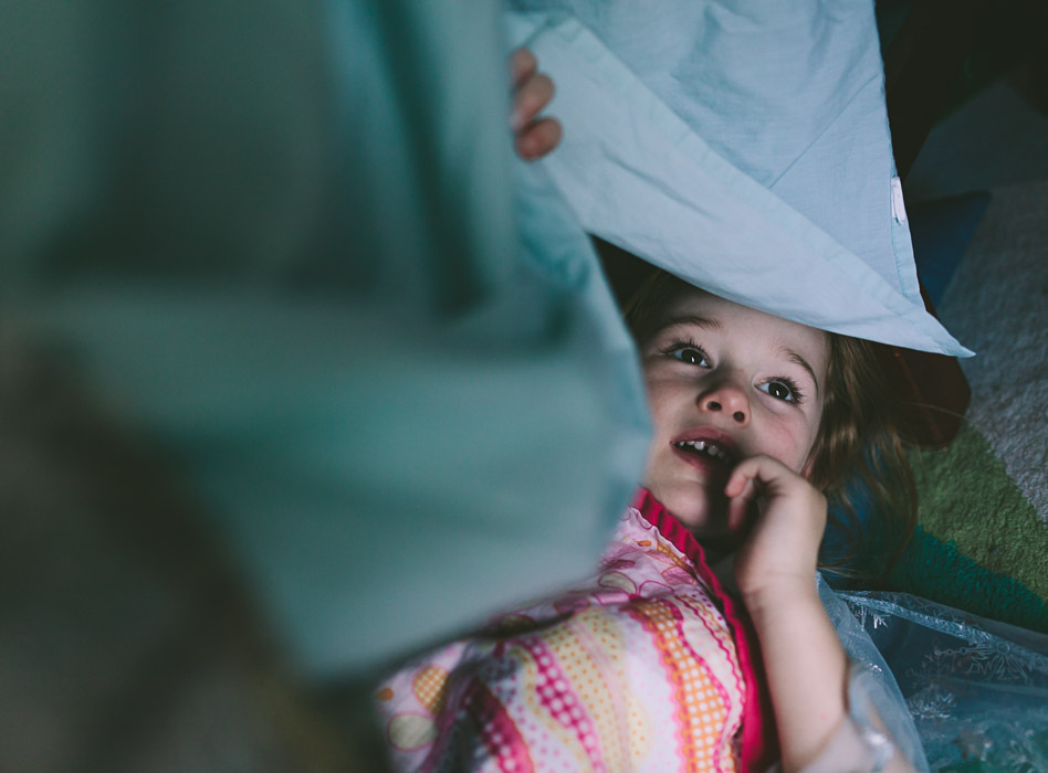 girl hiding under pillows