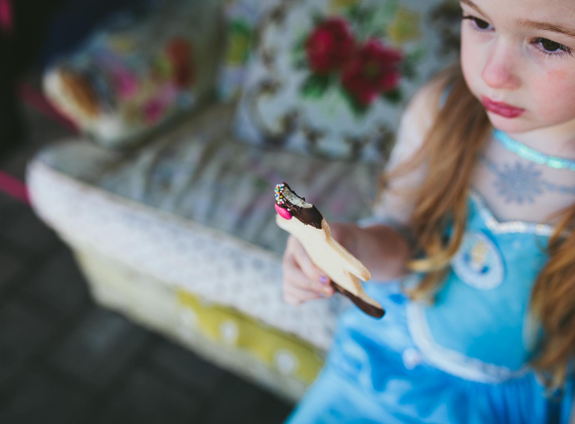 girl dressed as queen elsa eats a gingerbread man