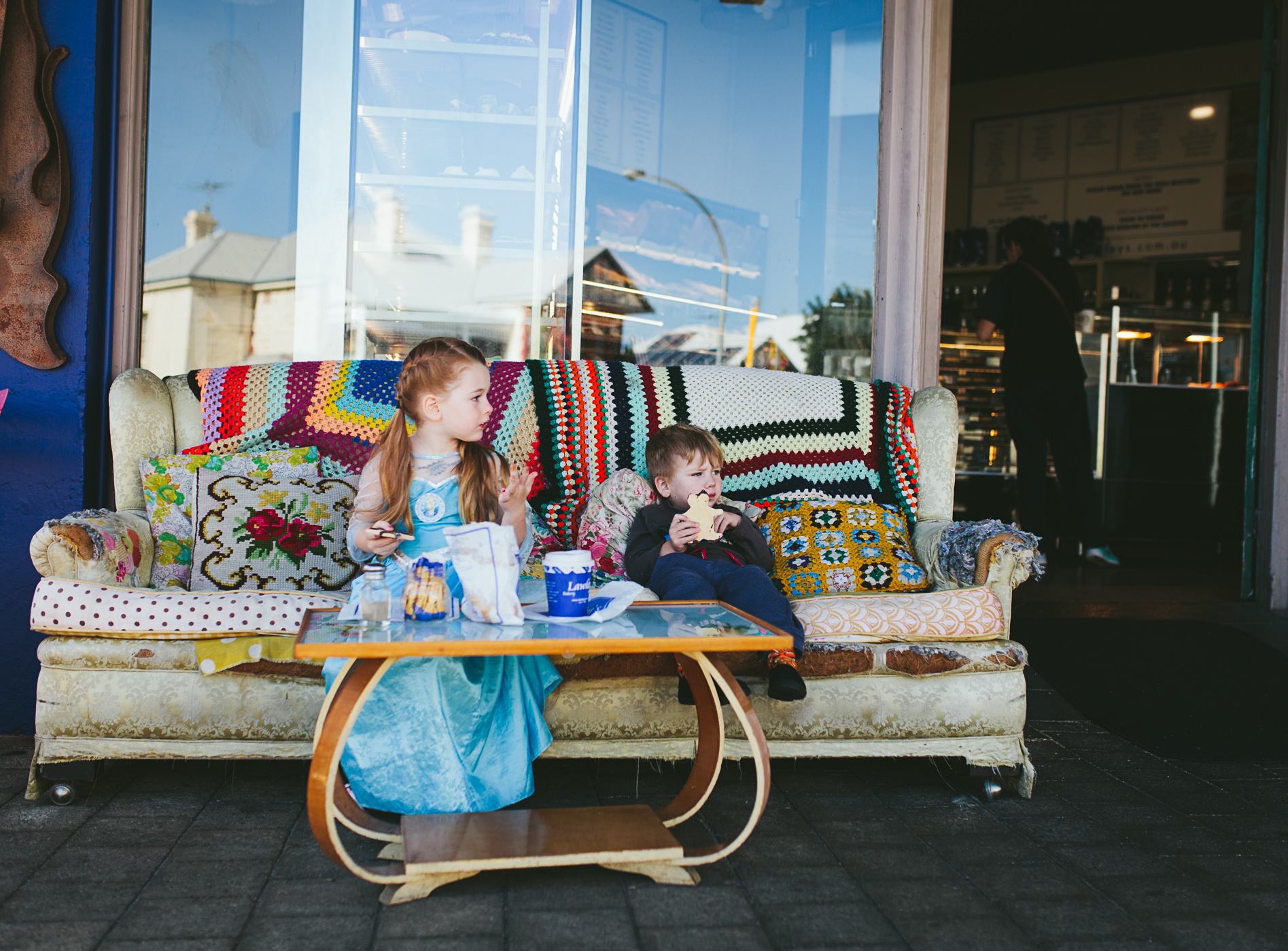 siblings sit on couch eating gingerbread man