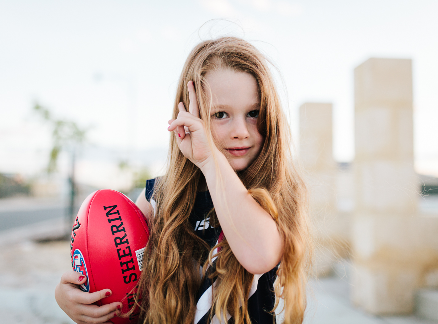 girl poses with sherrin football at documentary photo session perth