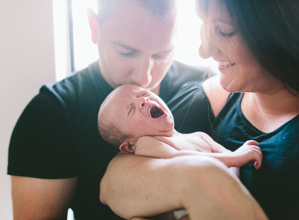 parents kiss baby 