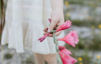 girl holding pink flower in white dress