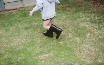 boy running on grass in black gumboots