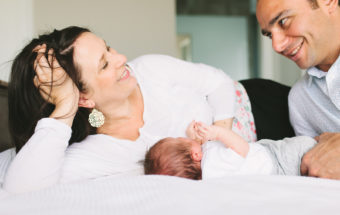 parents laying on bed with newborn baby